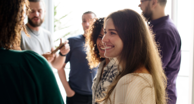 A group of people standing together and smiling in a bright office space.