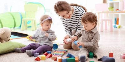 woman playing building blocks with young children