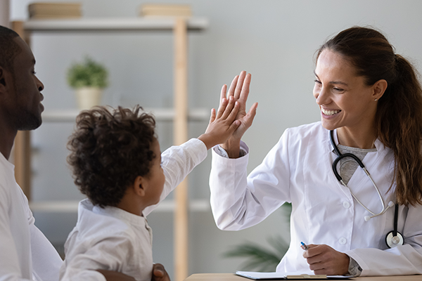 Image of a little boy giving a doctor a high five