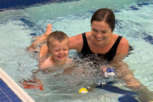 Therapist swimming with child in therapy pool
