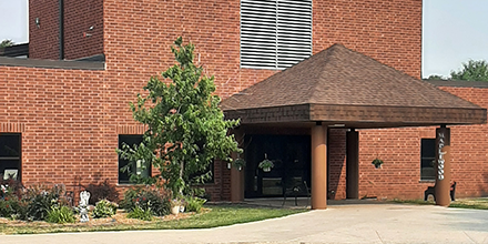 Photo of Maplewood residential building with red brick and trees surrounding entrance