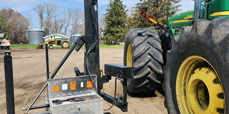 John Deere tractor on a farm with a lift attachment into the cab.