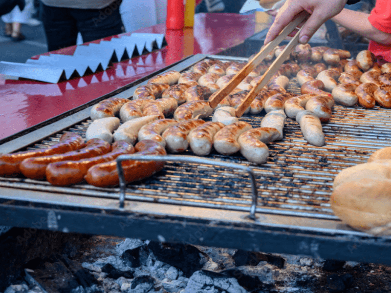 A person grilling sausages.