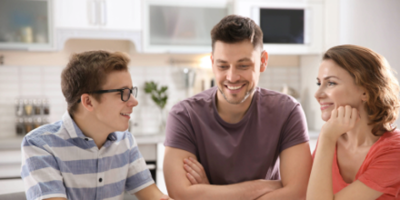 Male teen sitting in the kitchen talking to his dad and mom