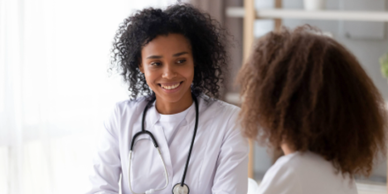 Black female physician talking to a black female teen
