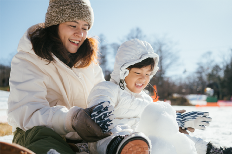 Image of a woman and a child building a snowman