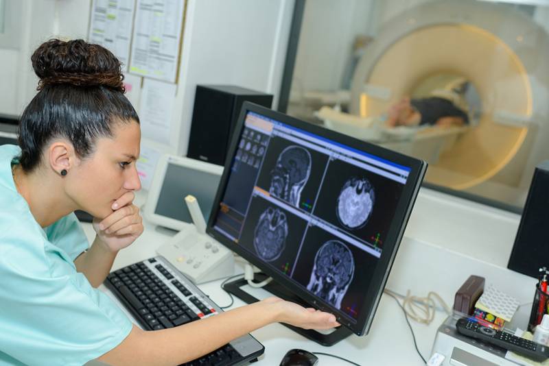 Medical worker reviews medical scans on a computer monitor