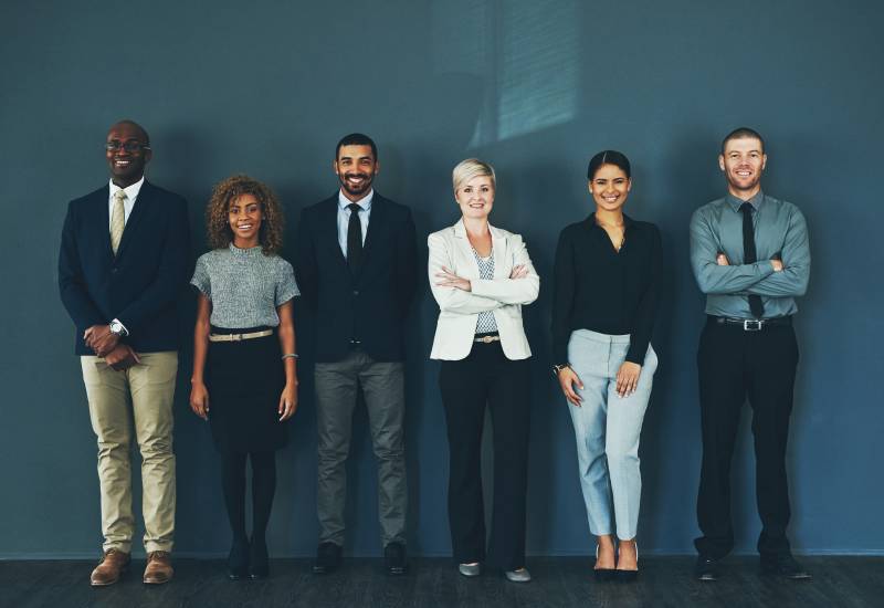 a diverse group of men and women standing against a wall