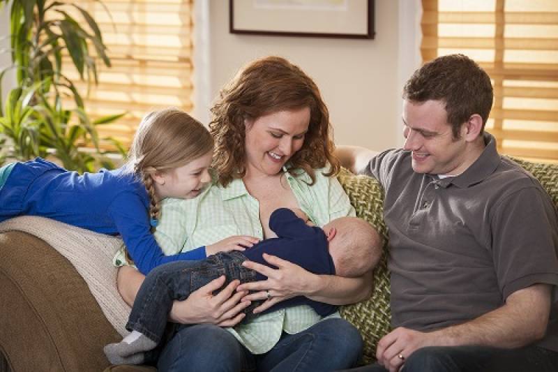 Breastfeeding mother with family on sofa