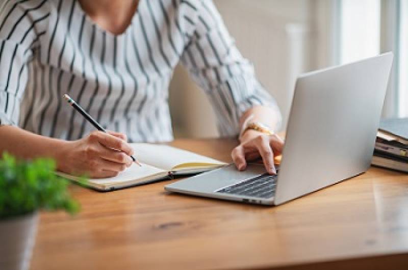 Person working on computer taking notes