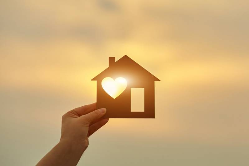 Hand holding house with a heart 