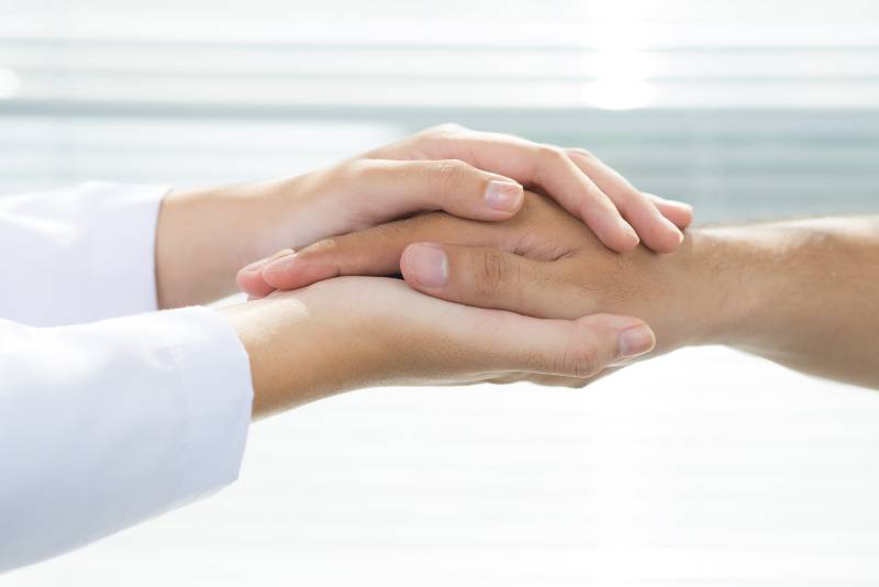 close up of hands of a health care provider holding a patient's hand