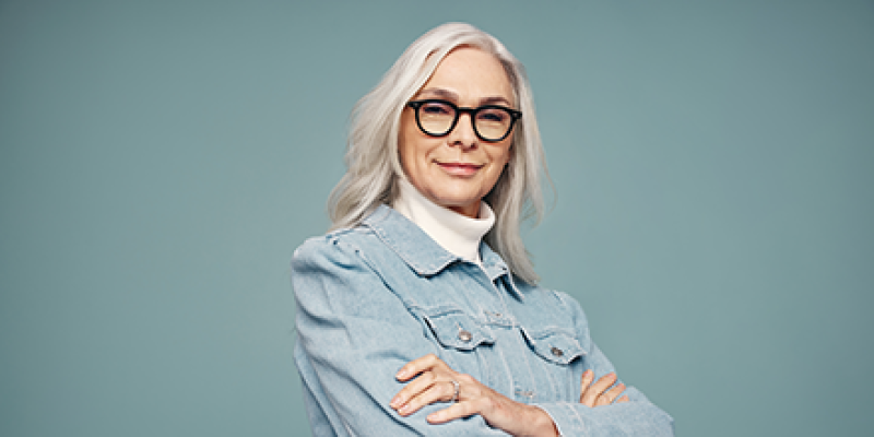 A senior woman with her arms crossed and smiling