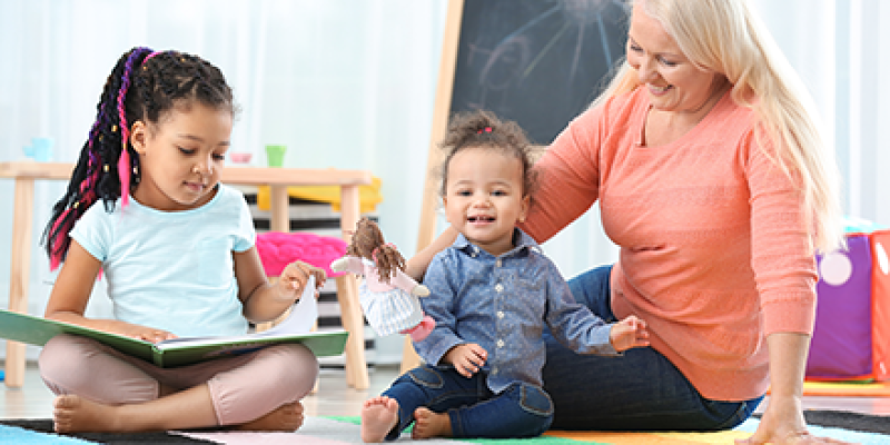 mature woman caregiver with two young children