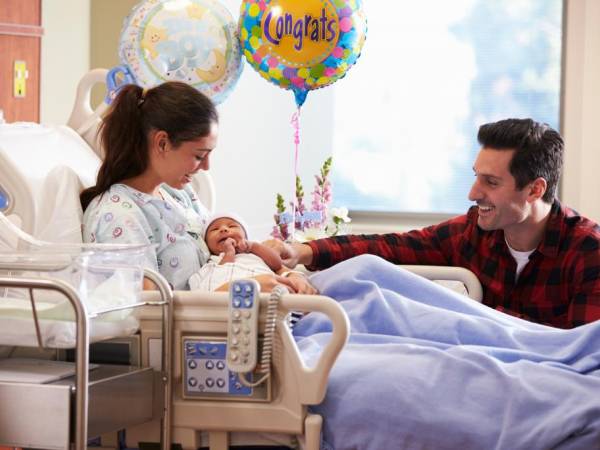 Young mother holding a baby in a hospital bed.