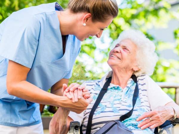 Caretaker attending to an elderly woman in a wheelchair.  