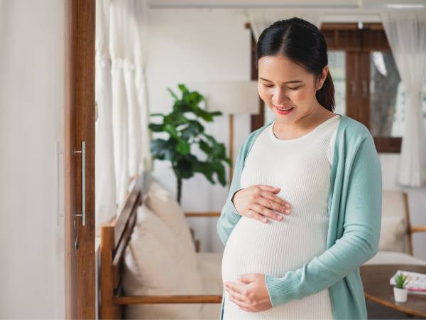 Pregnant woman holding and looking down at her belly