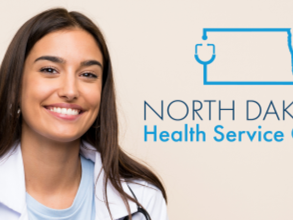 Young woman in a while physician coat with a stethoscope next to the ND Health Services Corps logo