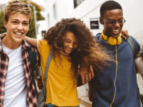 Group of smiling teens, 2 male and 2 female, smiling as they walk together
