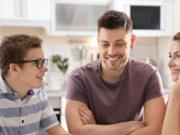 Male teen sitting in the kitchen talking to his dad and mom