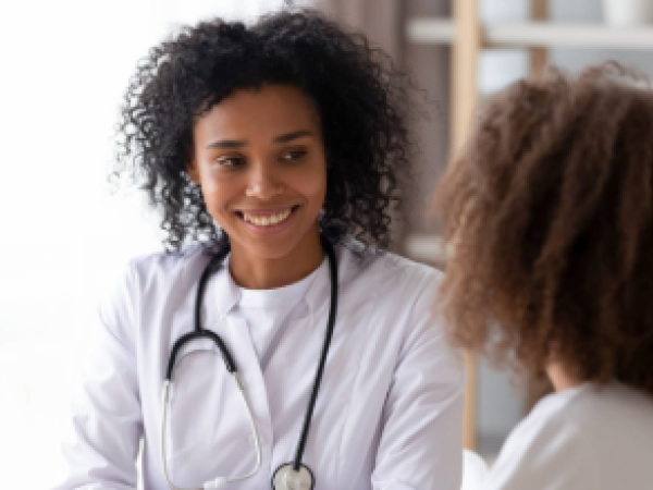 Black female physician talking to a black female teen