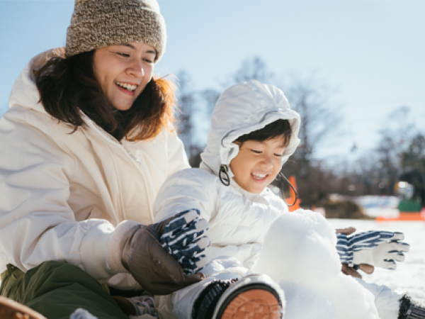 Image of a woman and a child building a snowman