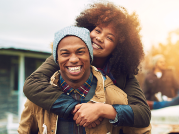 Image of a man smiling and a woman with her arms around his shoulders