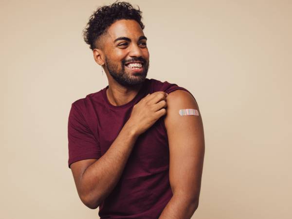 A man showcases a bandage on his arm from getting immunized