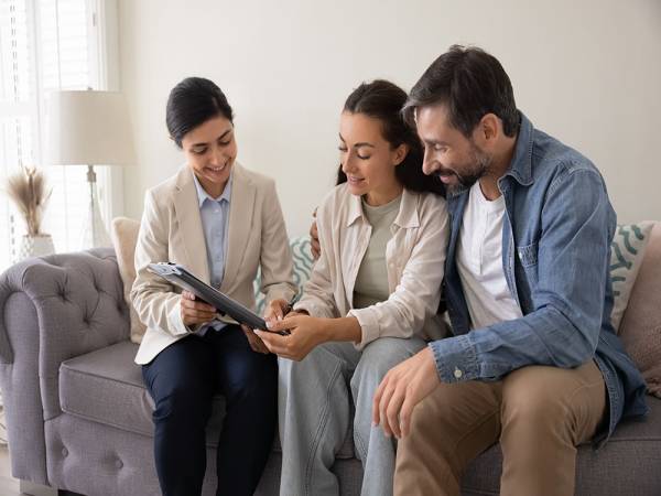 Two people filling out forms with assistance from another woman.