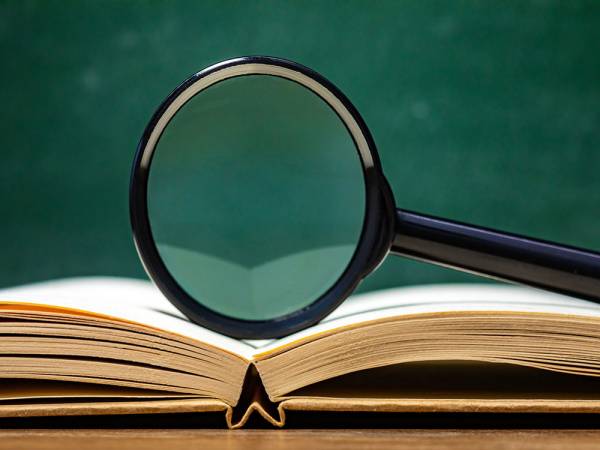 Magnifying class sitting vertically on an open book