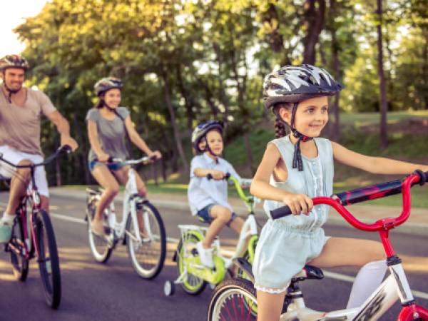 two adults and two children riding bikes while wearing helmets
