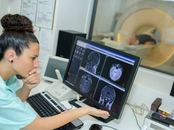 Medical worker reviews medical scans on a computer monitor
