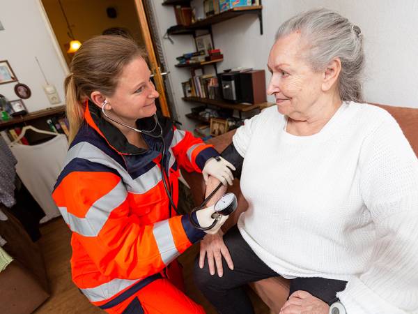 An older person is assisted by a paramedic in the home