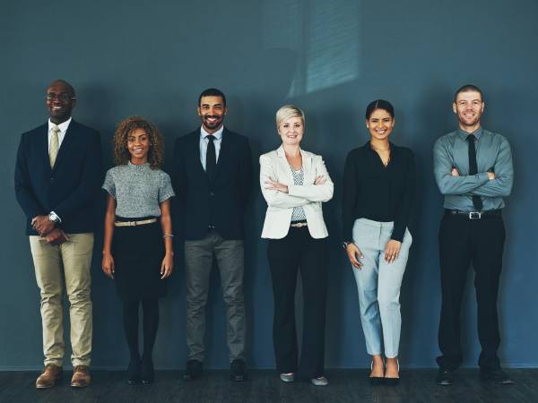 a diverse group of men and women standing against a wall