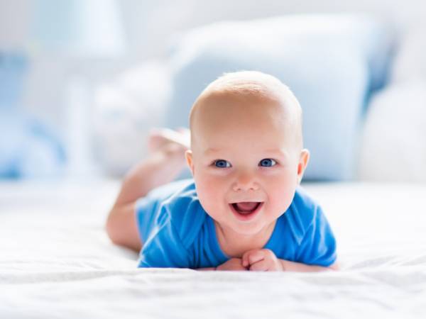baby laying on tummy with head lifted to smile at the camera