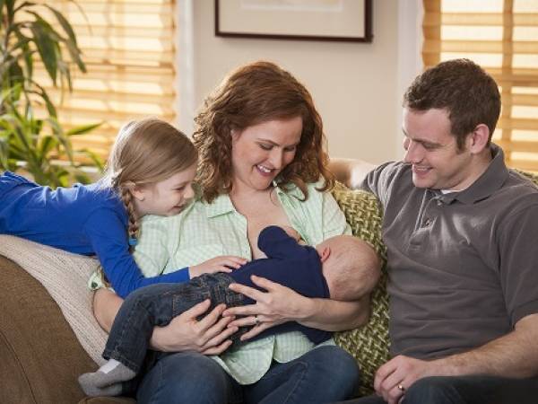 Breastfeeding mother with family on sofa