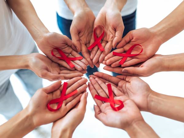 Hands in a circle each holding red ribbon
