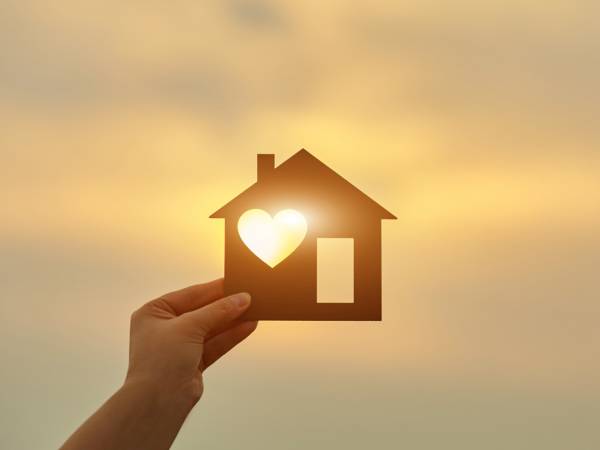 Hand holding house with a heart 