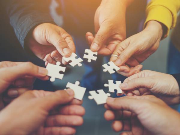 Circle of hands with people hold puzzle pieces