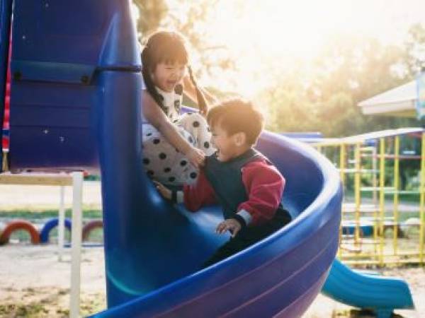 Children riding down a blue slide