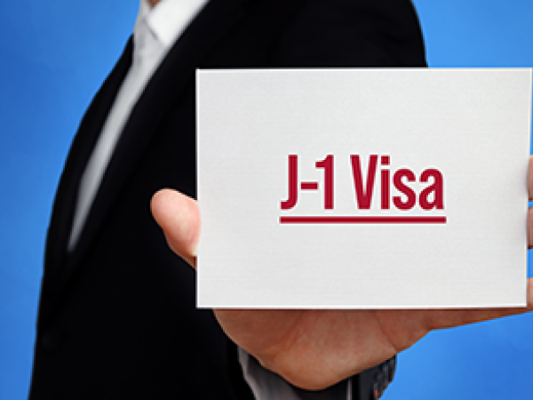 Man holding white card with text J-1 Visa