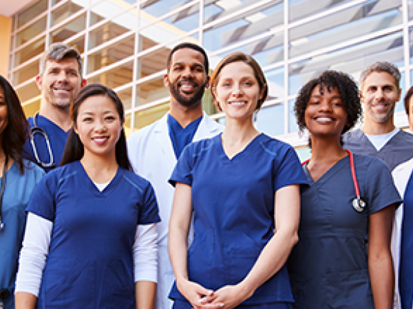 A group of various health care providers standing in front of a medical facility