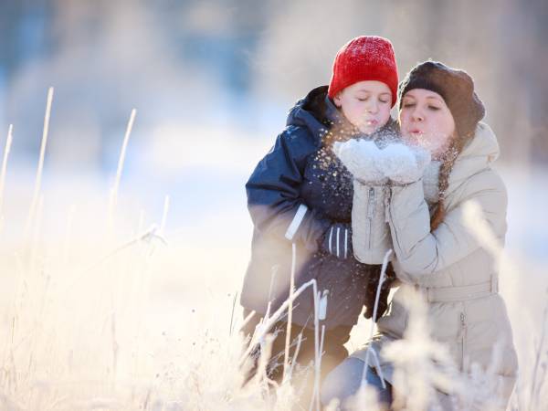 a child plays in the snow with a parent