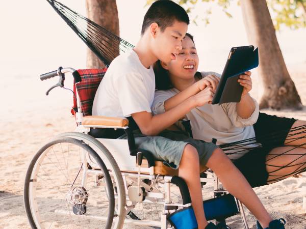a young man in a wheelchair with another person outside