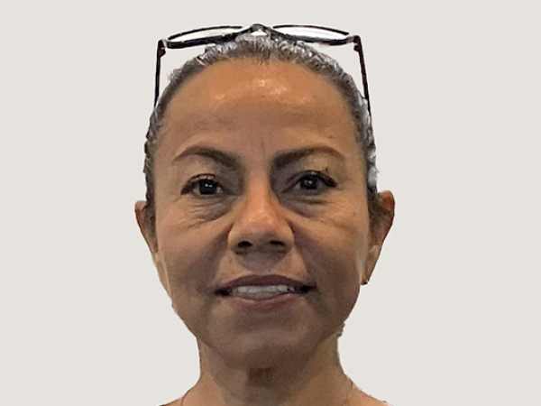 Medium skinned female with hair pulled back in and ponytail and glasses on the top of her head.