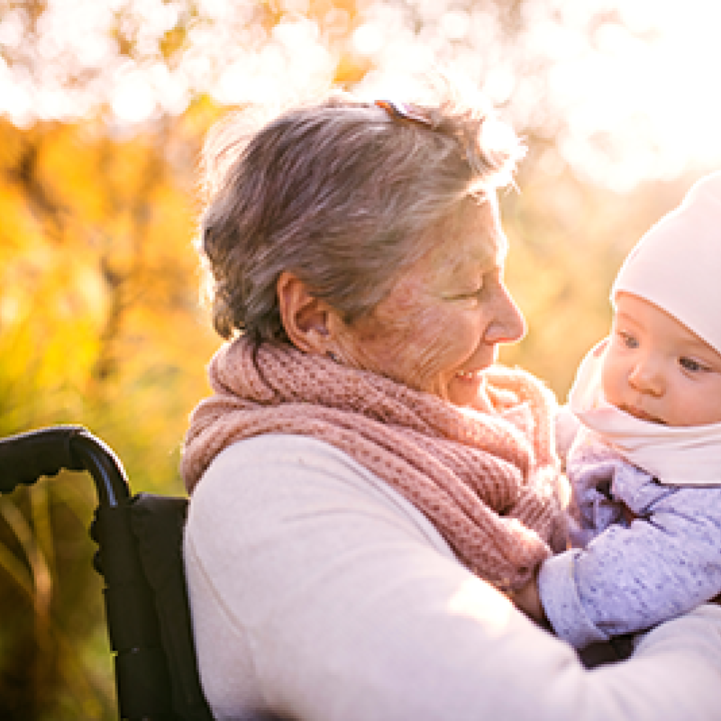 A grandma in a wheelchair holds her baby granddaughter.