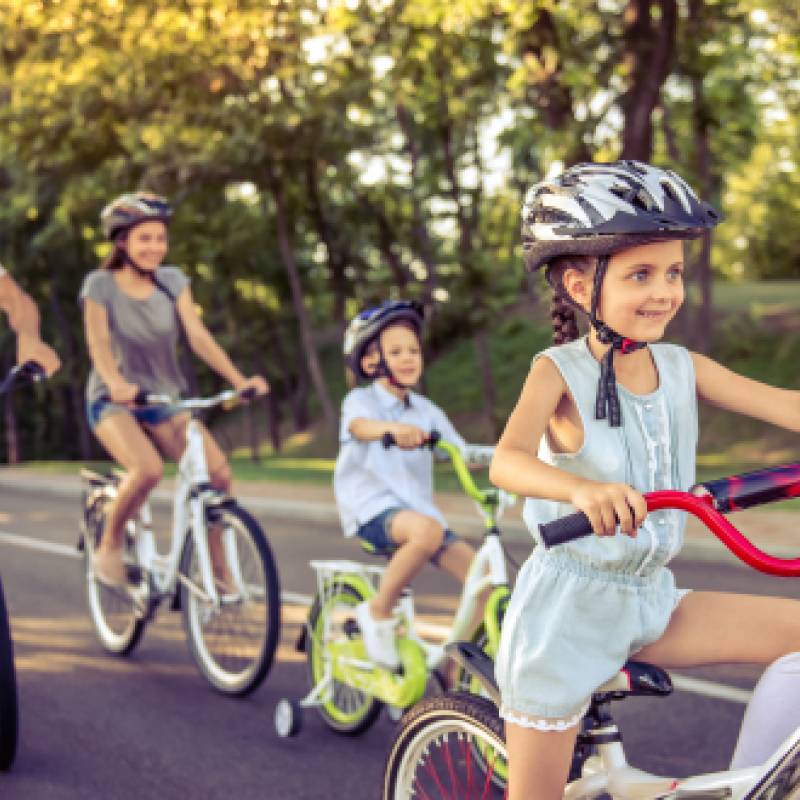 two adults and two children riding bikes while wearing helmets