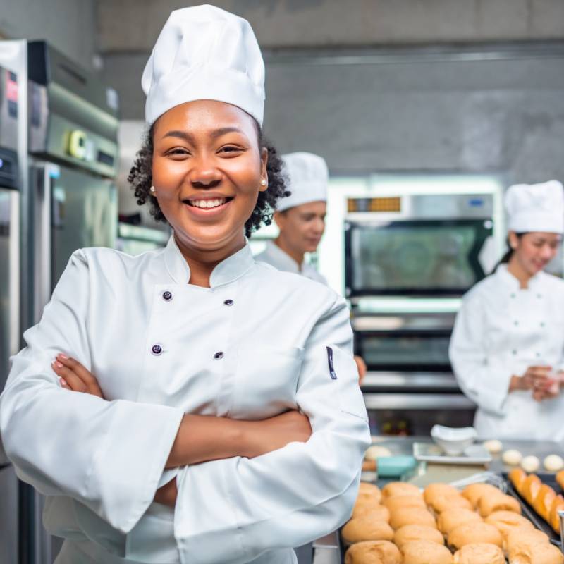female chef standing in kitchen surrounded by baked rolls