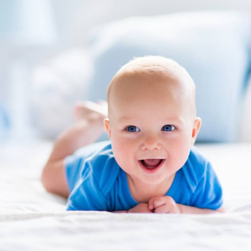 baby laying on tummy with head lifted to smile at the camera