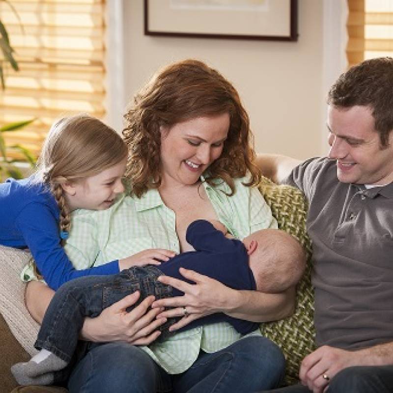 Breastfeeding mother with family on sofa